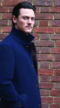 Люк Эванс, актер, синий плащ, кирпичная стена, взгляд (vertical)